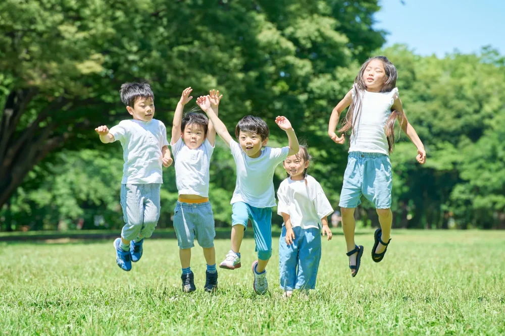 芝生の上でジャンプする子どもたち