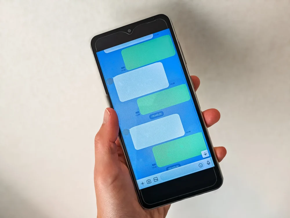チャット画面が表示されたスマートフォンを持つ手